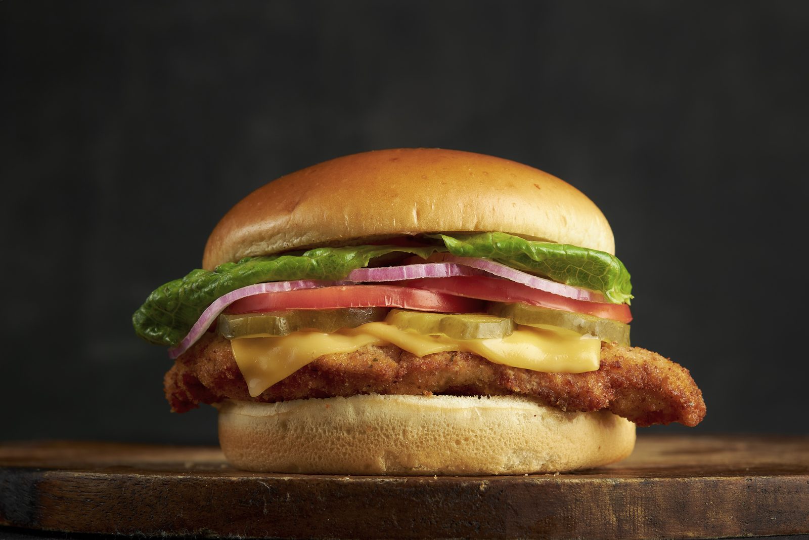 Crispy chicken milanesa sandwich with lettuce, tomato and red onion