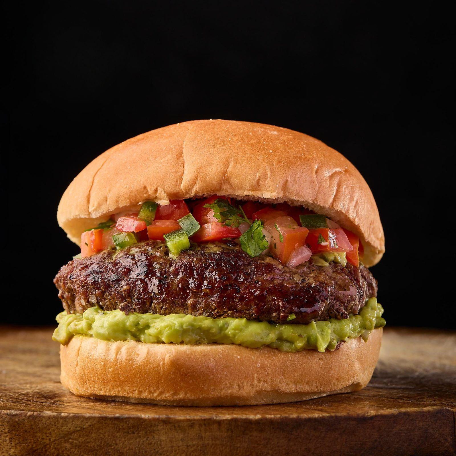Burger topped with fresh guacamole and pico de gallo