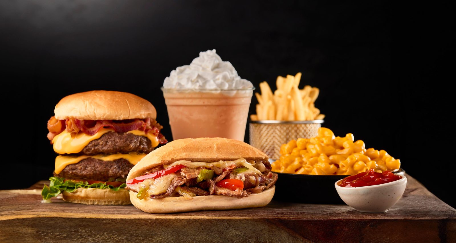 Family spread with burgers, a sandwich, fries, mac and cheese and a milkshake