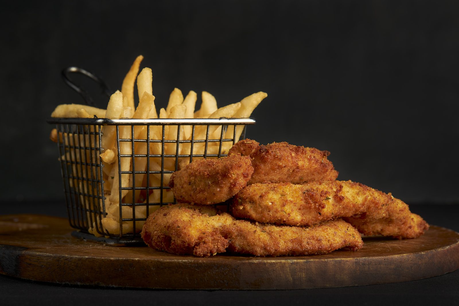 Hand-breaded chicken tenders with a basket of golden fries
