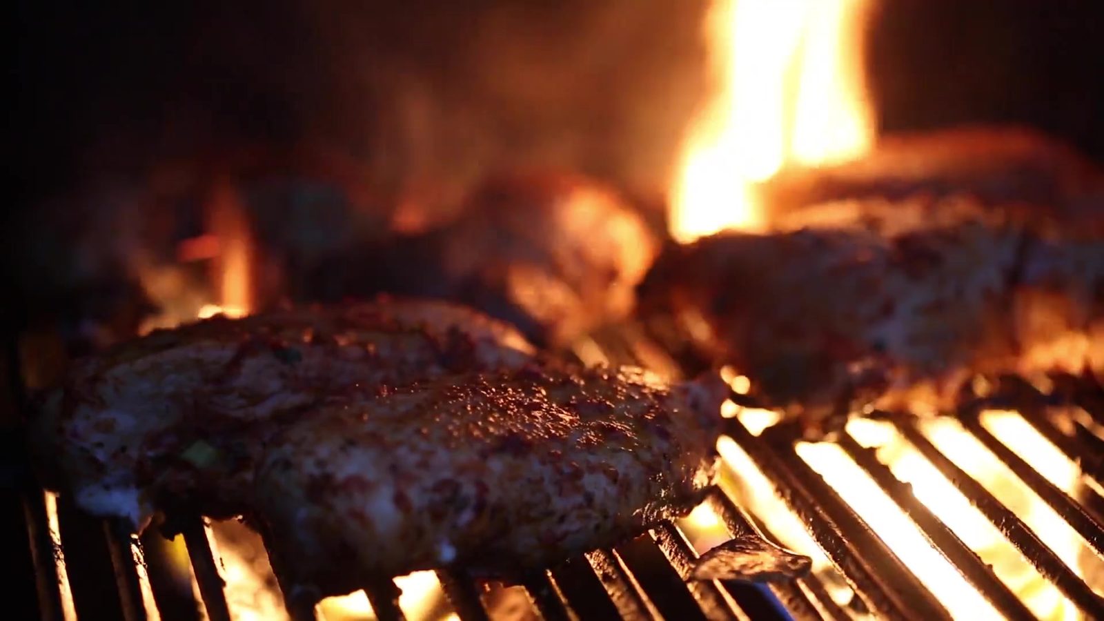 Beef patties searing over open flame on the grill